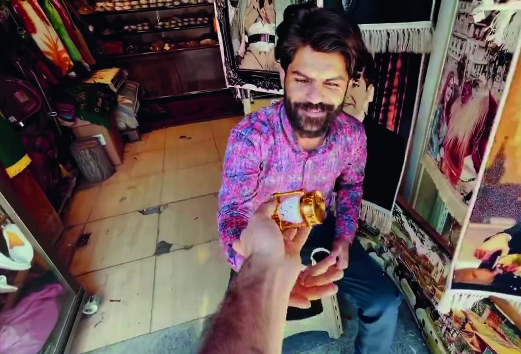 A smiling shopkeeper receives a Ramadan lantern